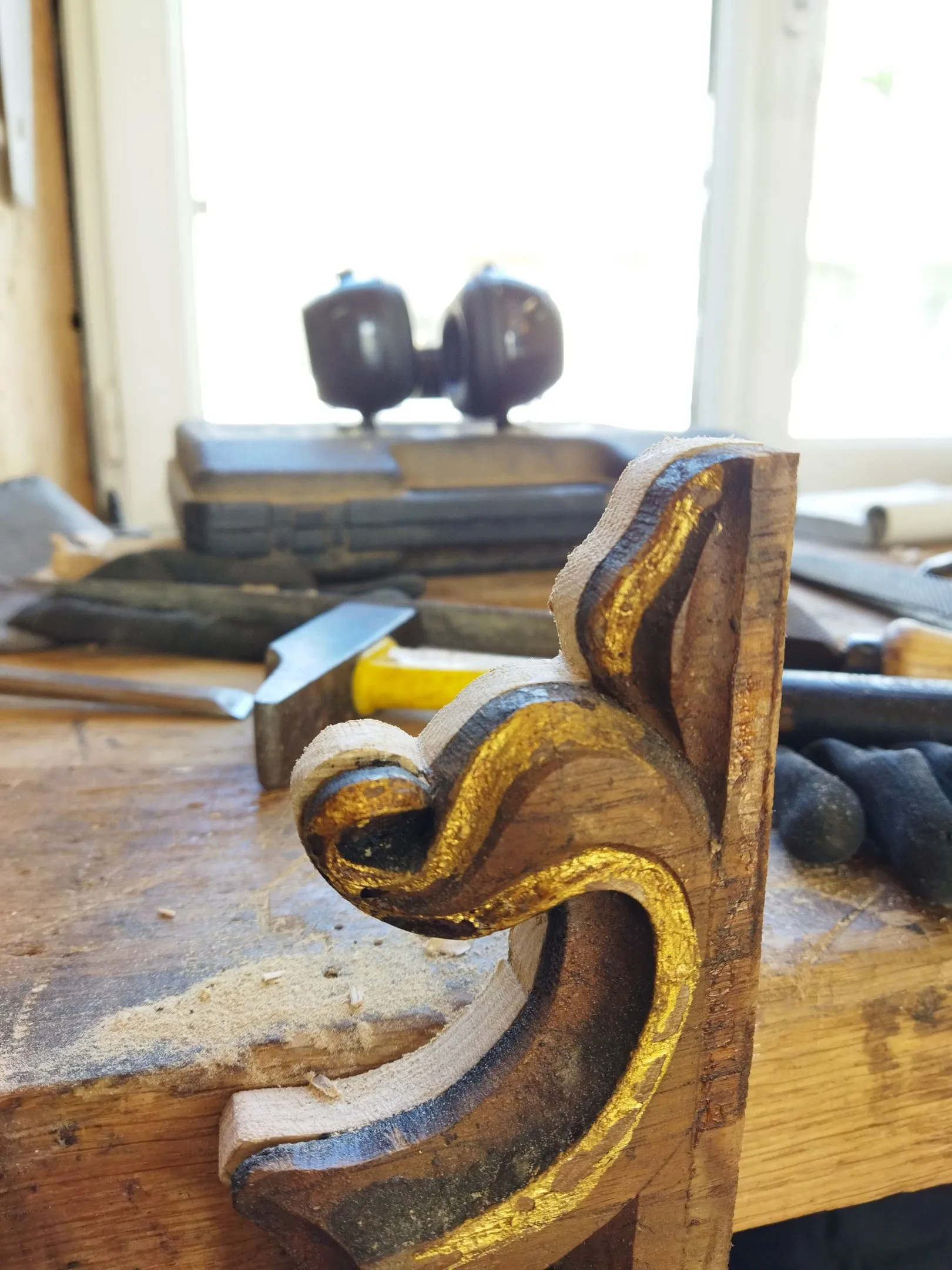 Détail d'un ornement sculpté et doré, restauré à la main sur l'établi