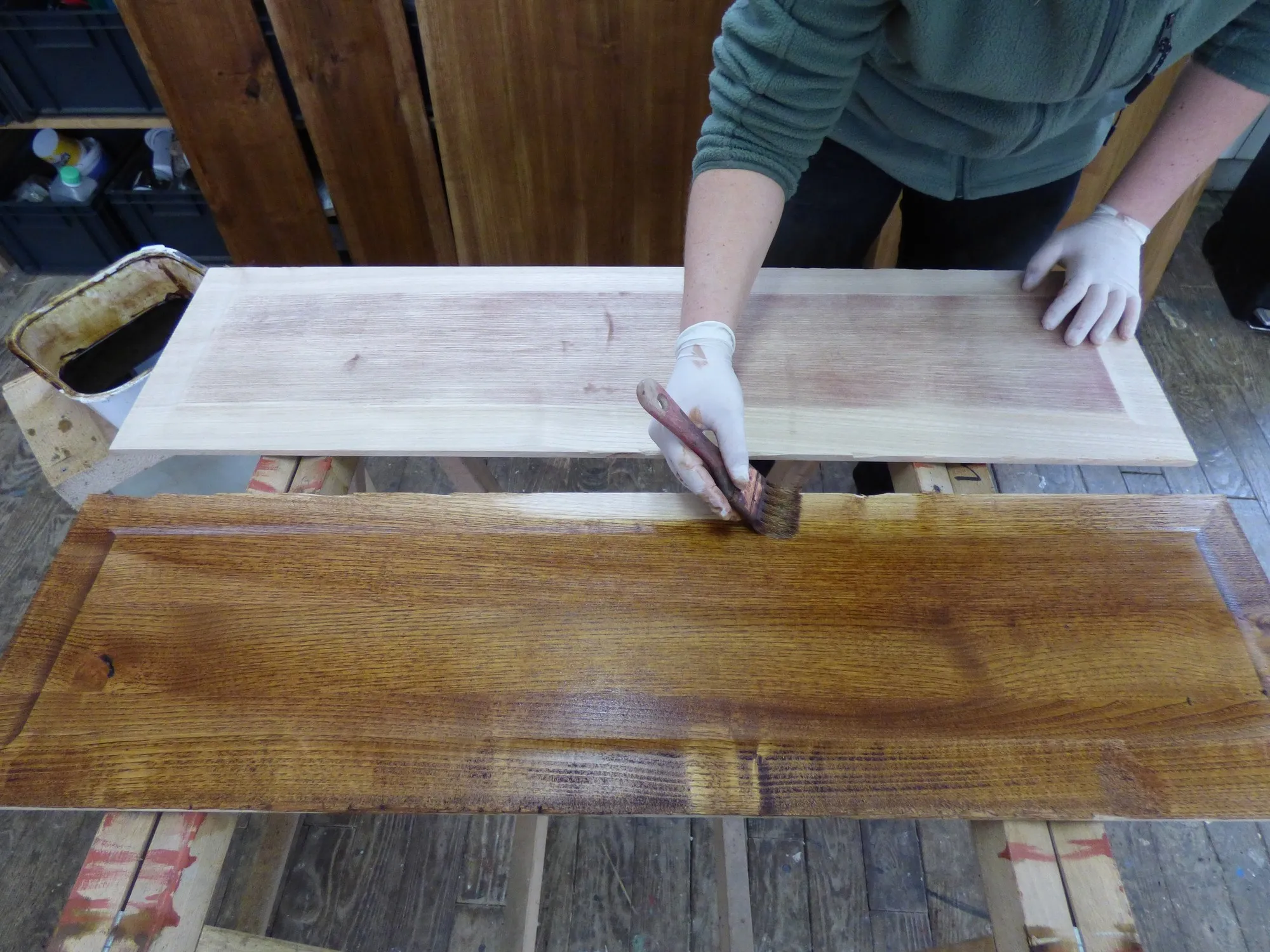 Océane Jean applique la finition sur des panneaux de bois dans son atelier